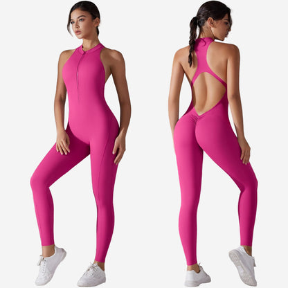 Woman wearing a bright pink jumpsuit with open back, standing against a grey background.