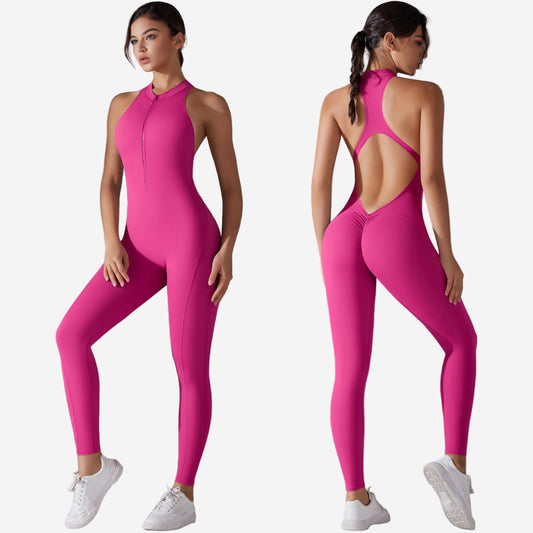 Woman wearing a bright pink jumpsuit with open back, standing against a grey background.